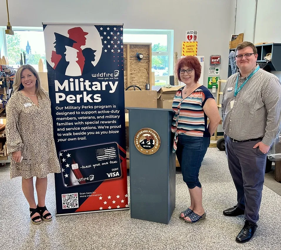 Wildfire employees stand next to Military Perks banner at Bay Veterans Foundation in Bay City.