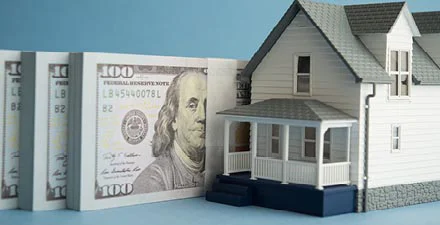 Model house placed next to several hundred dollar bills.