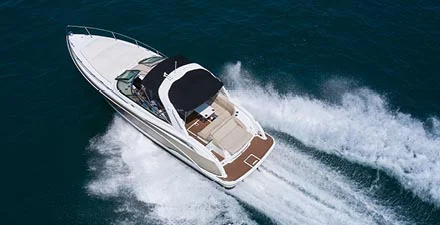 White speedboat cruising across the water, leaving a wake behind at aerial view.