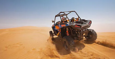 Side-by-Side UTV throwing dust at top of Michigan Sand Dunes.