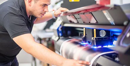 Man operating a large-format printer producing a colorful print.