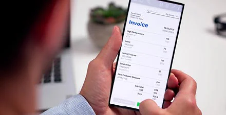 Person viewing an invoice on a smartphone screen in a well-lit office setting.