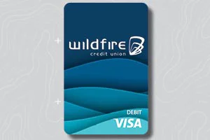 Dark blue Wildfire Credit Union debit Visa card with wave design on gray topo background.
