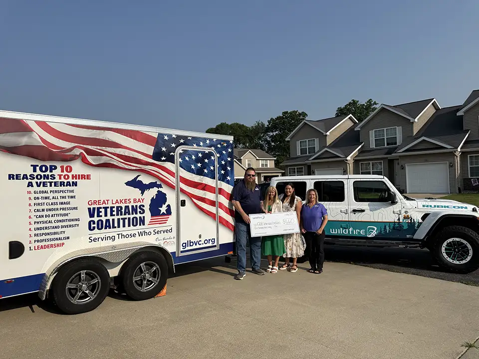 Two Wildfire employees in front Jeep present check to Great Lakes Bay Veterans Coalition