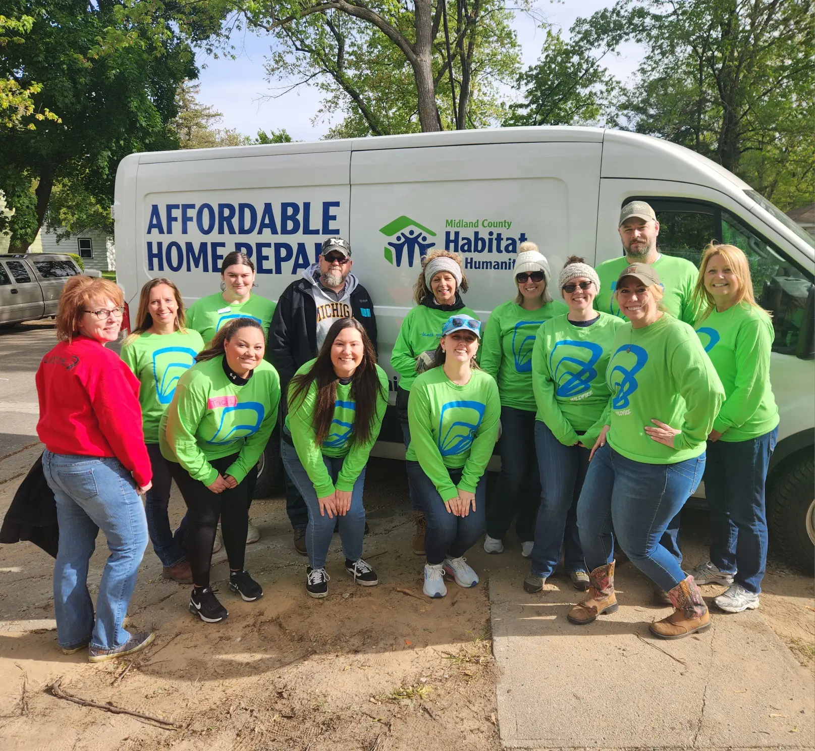 Wildfire team in green shirts in front of Midland Habitat for Humanity van all smiling.