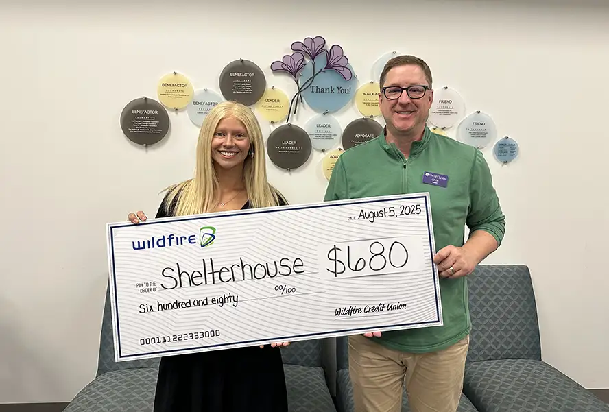 Smiling Wildfire employee presents check to Shelterhouse.