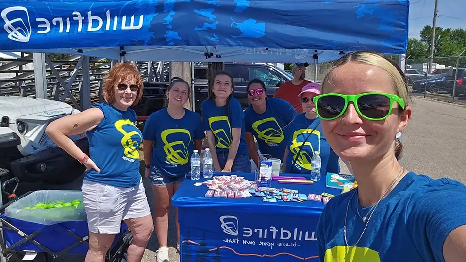 Six Wildfire employees outside wearing matching blue shirts in front of Wildfire prize booth at St. Stan's Festival.