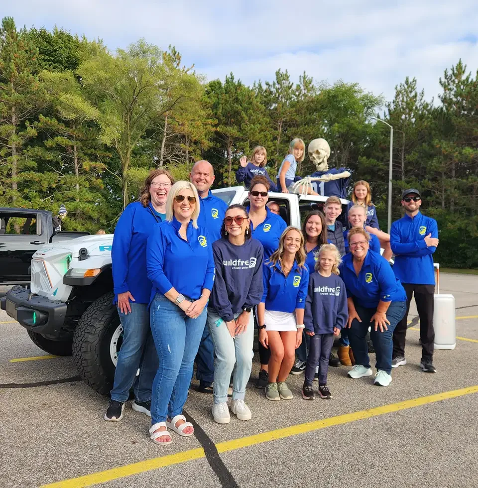 Wildfire employees in front of Jeep all standing and smiling outside after Hemlock parade.