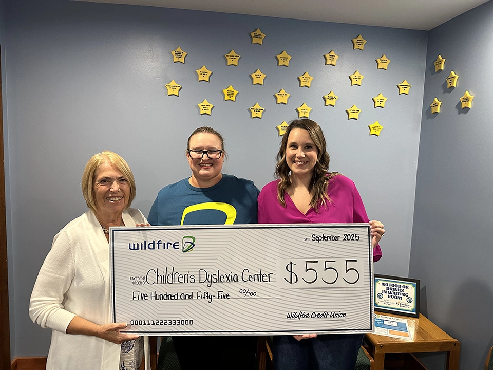 Wildfire employee and employees from Children's Dyslexia Center holding $555 check.