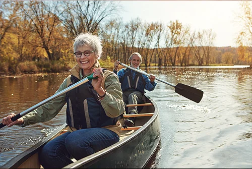 Couple out on a canoe enjoying nature in the fall on a river.