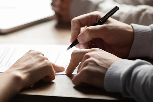 Person pointing to where they need to sign documents with pen.