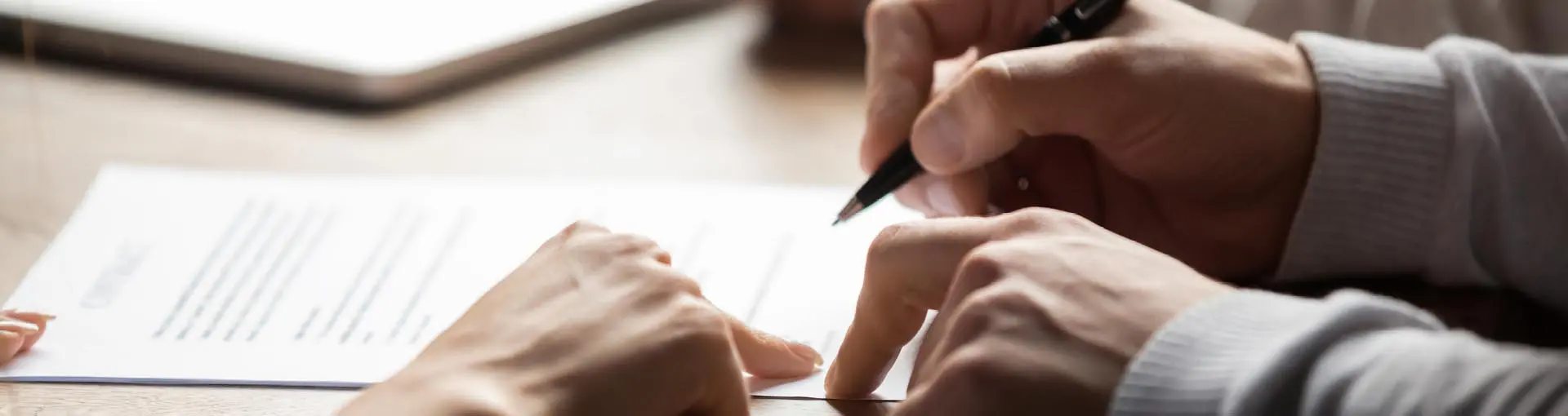 Two people reviewing and signing a legal document together.