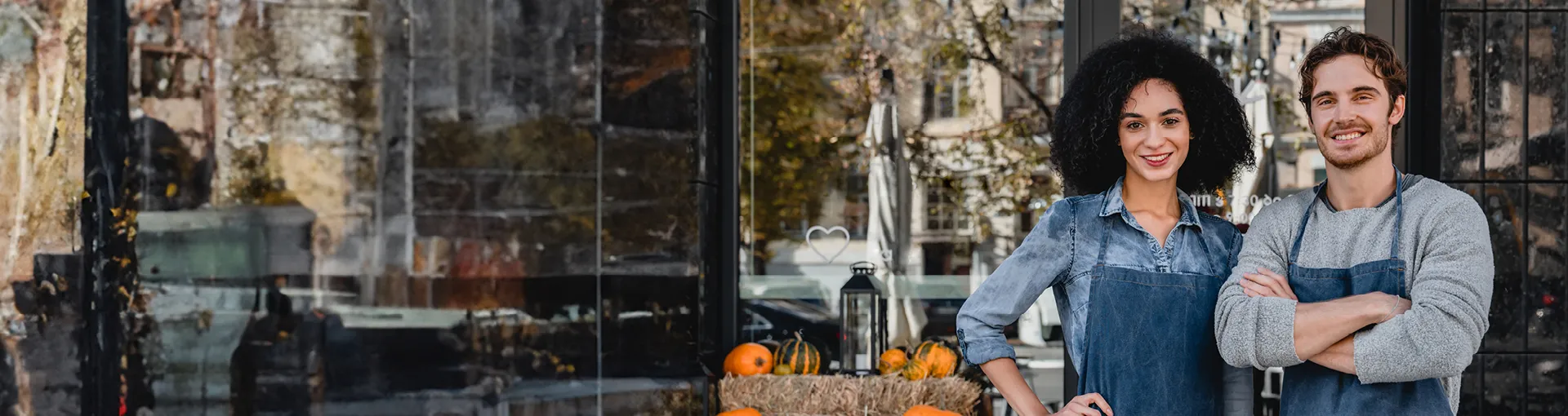 Local business couple standing outside their storefront in the fall.