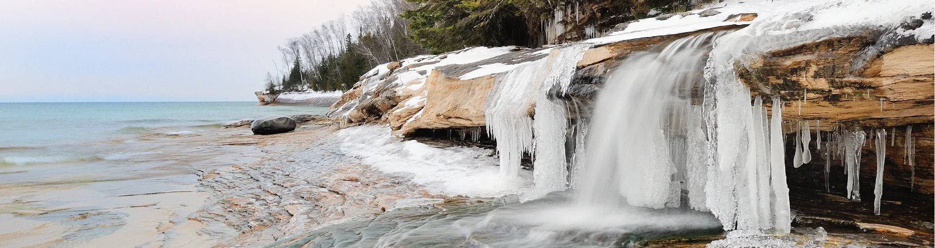 Frozen ice on rocks from river leading into Lake Superior from the shore.