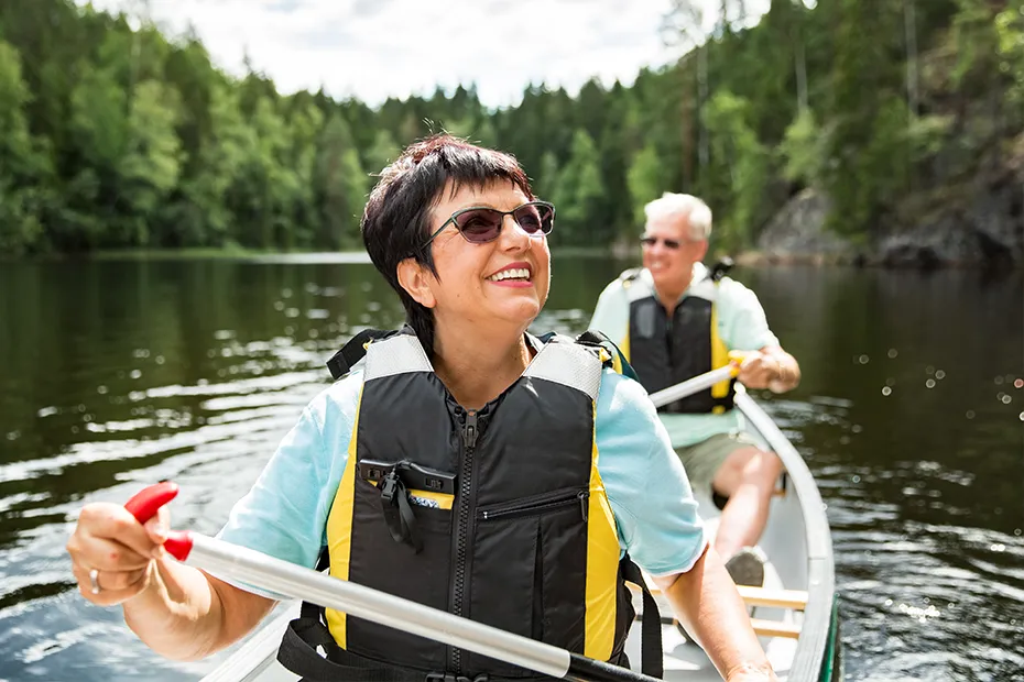 Couple canoeing together on Michigan lake surrounded by pine trees.