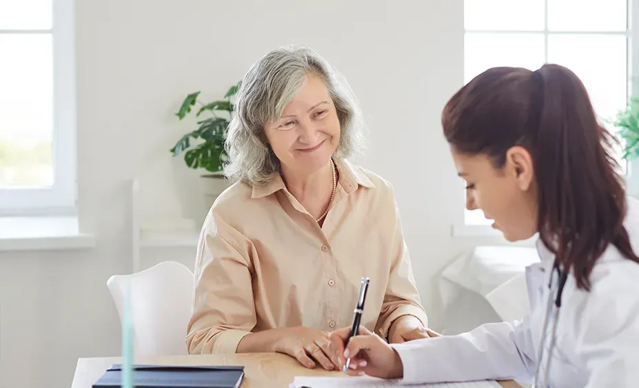 Doctor taking notes for patient on a health chart in white room with windows.